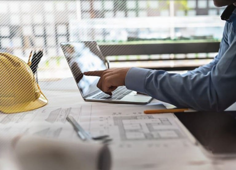 Desk with Laptop Computer, Roofing Blue Print, and a Yellow Hard Hat