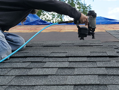 Roof Installer Using a Nail Gun to Install Shingles